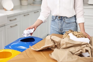 Photo of Woman separating garbage at wooden table indoors, closeup