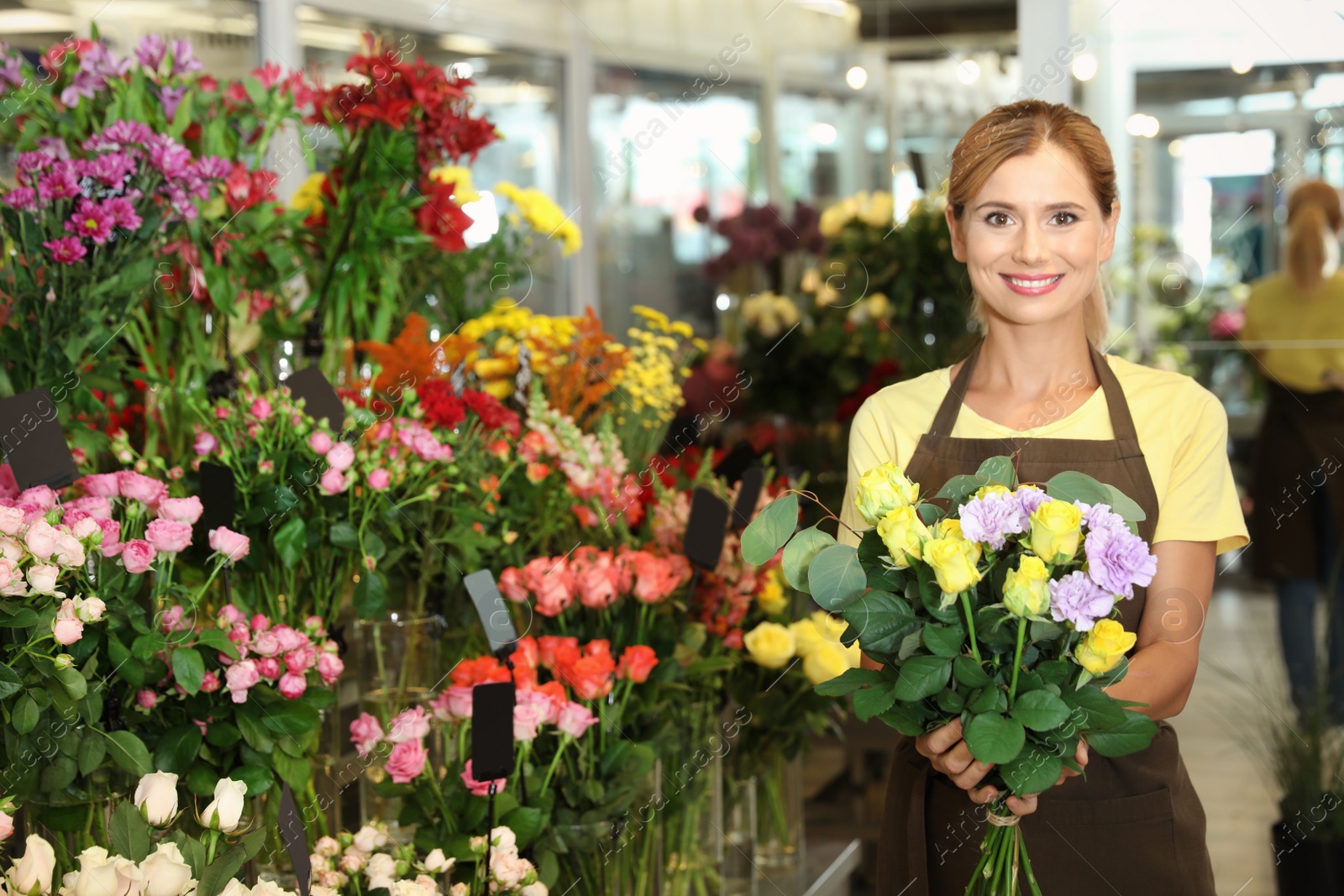 Photo of Female florist holding beautiful bouquet in flower shop