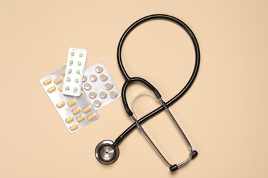 Stethoscope and pills on beige background, flat lay. Medical tool