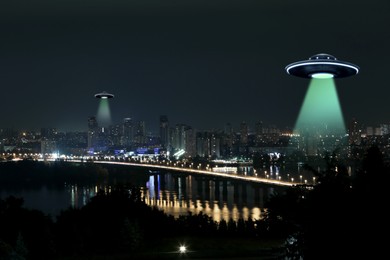 Image of UFO. Alien spaceships emitting light beams over night city