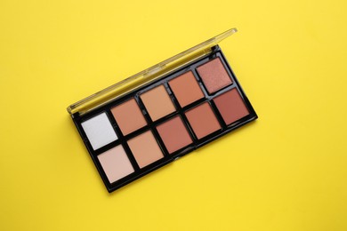 Photo of Colorful contouring palette on yellow background, top view. Professional cosmetic product