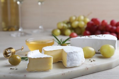 Photo of Tasty brie cheese with olives and grapes on white board