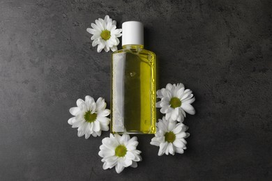 Photo of Fresh mouthwash in bottle and flowers on dark textured table, top view