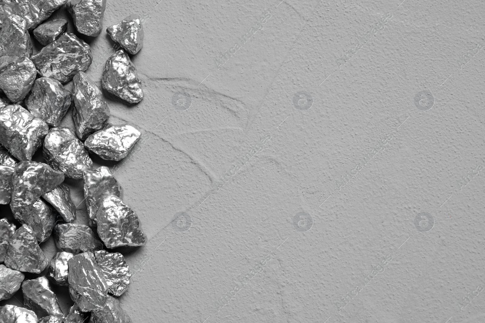 Photo of Pile of silver nuggets on grey table, flat lay. Space for text