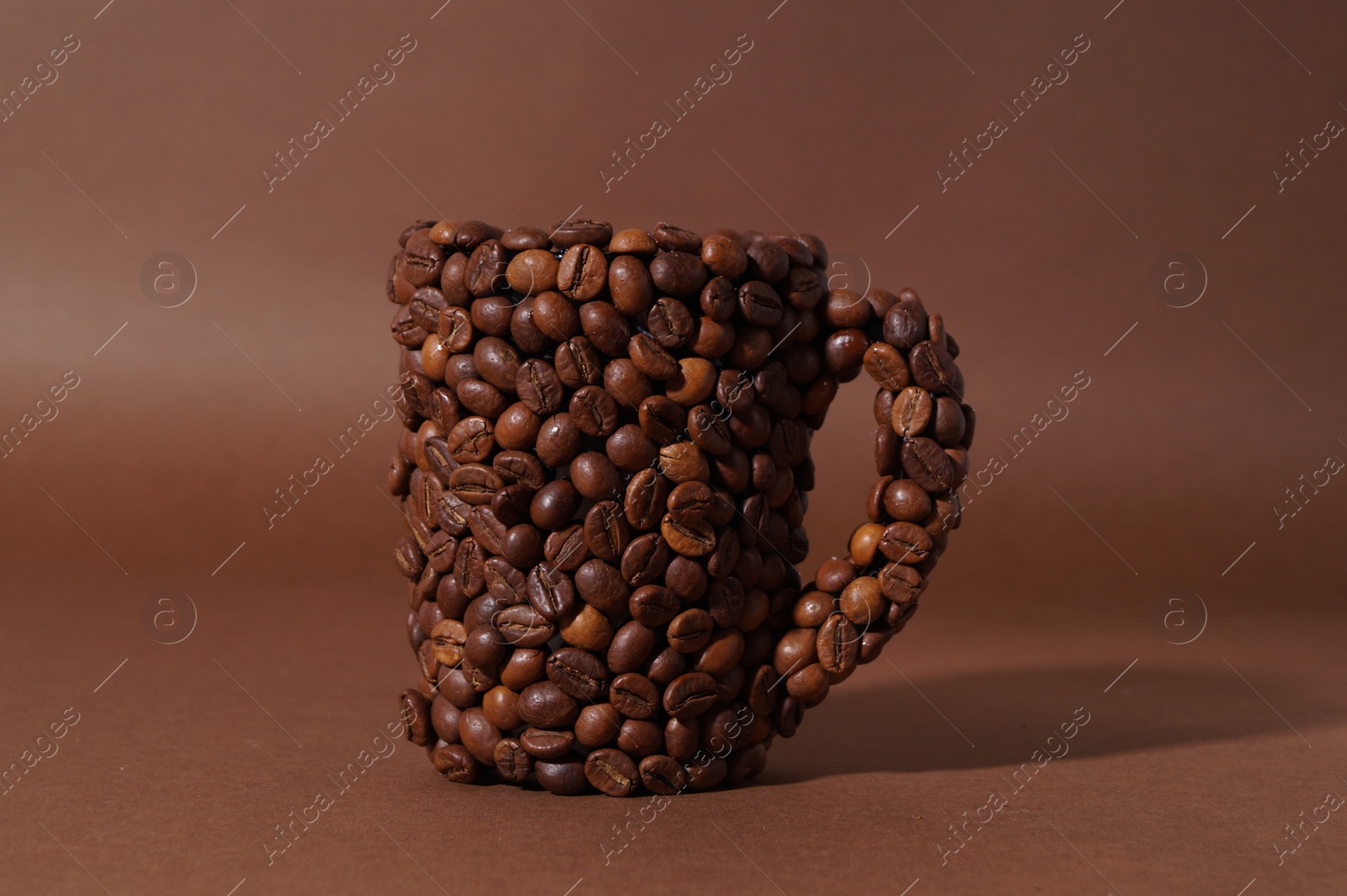 Photo of Cup made of coffee beans on brown background