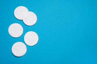 Photo of Many cotton pads on light blue background, flat lay. Space for text