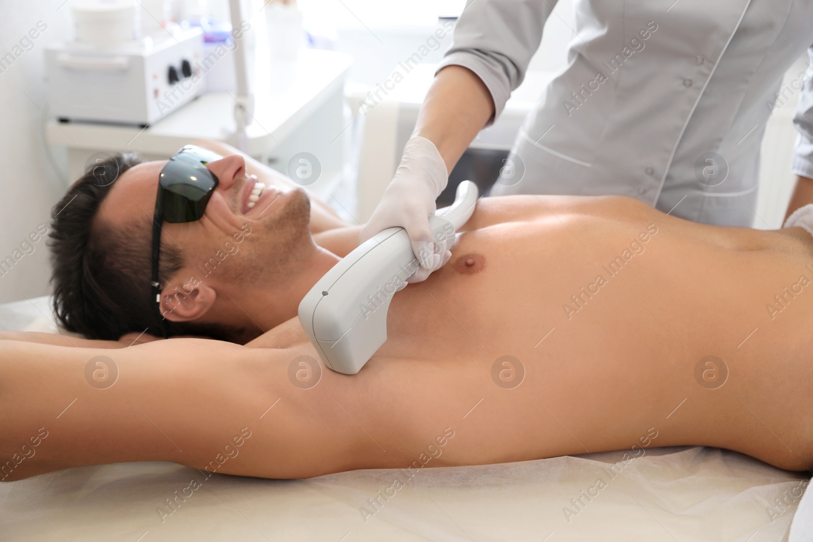 Photo of Young man undergoing laser epilation procedure in beauty salon