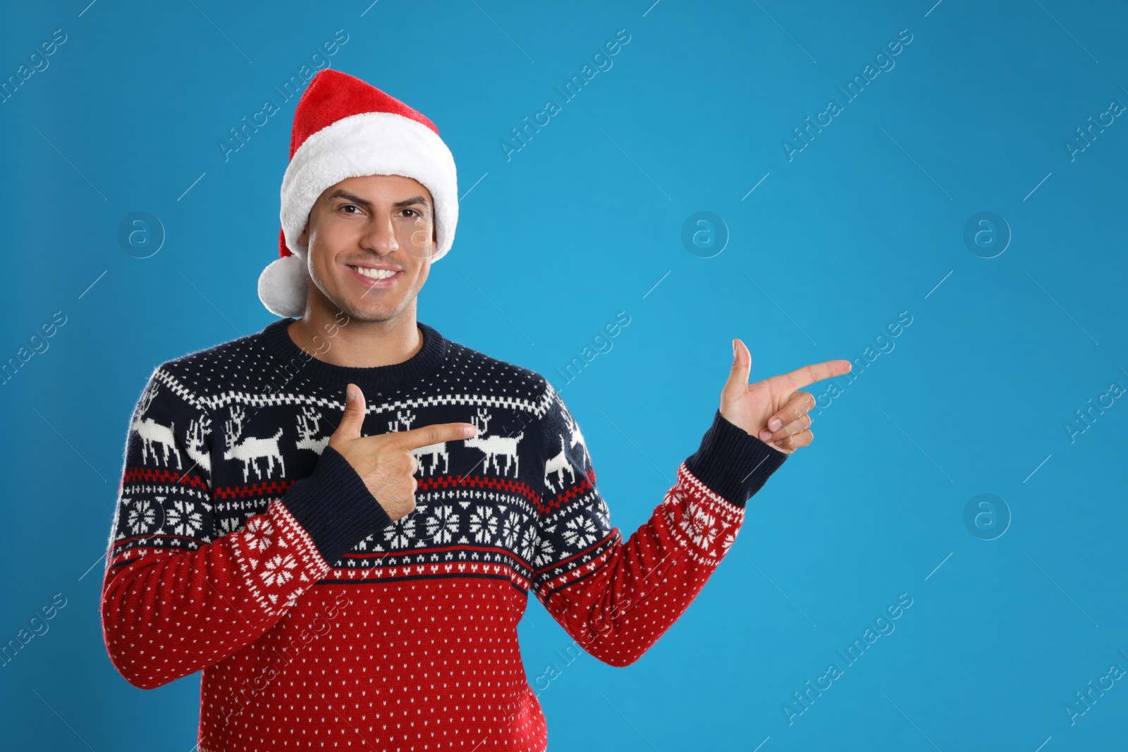 Photo of Happy man in Santa hat on blue background. Christmas countdown