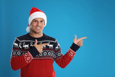 Photo of Happy man in Santa hat on blue background. Christmas countdown