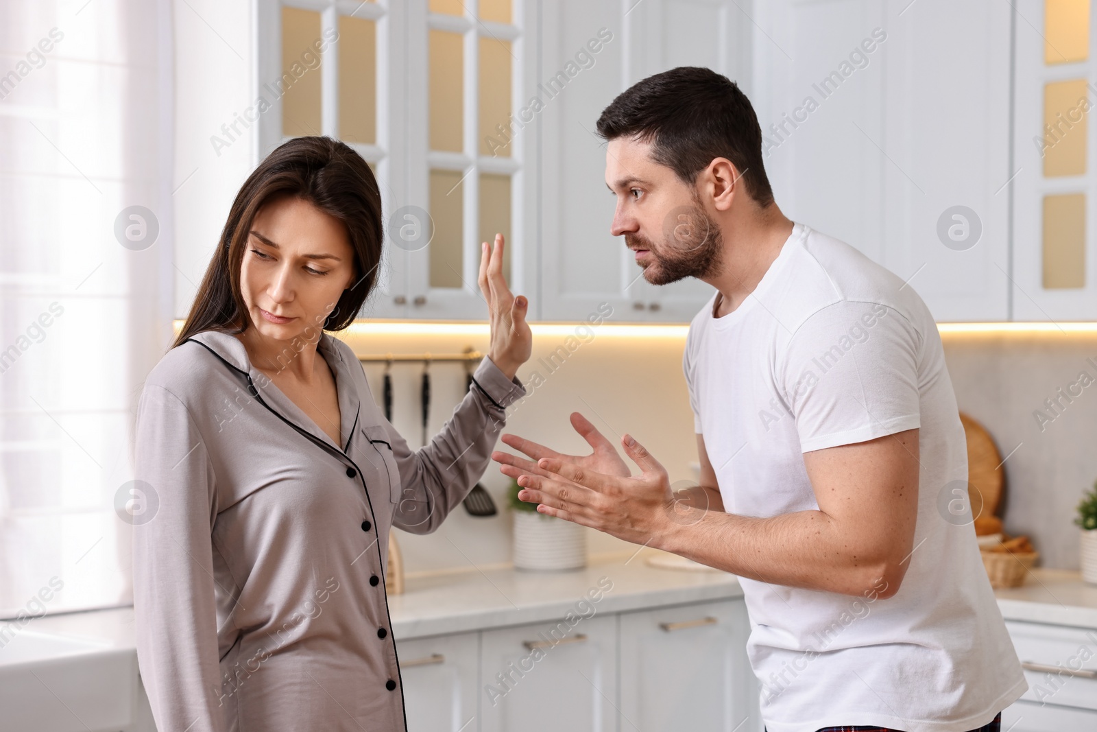 Photo of Tired wife stopping her husband in kitchen. Relationship problems