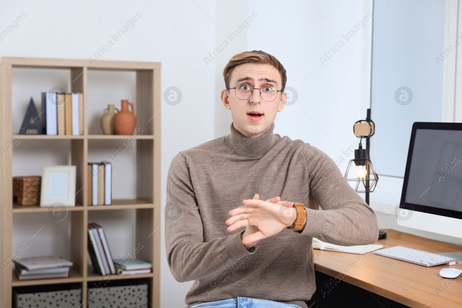 Photo of Emotional young man checking time in office. Being late