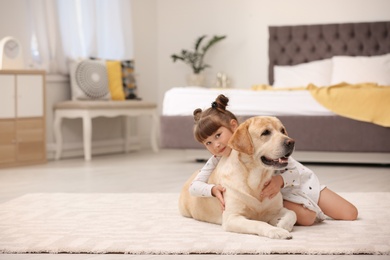 Adorable yellow labrador retriever and little girl at home