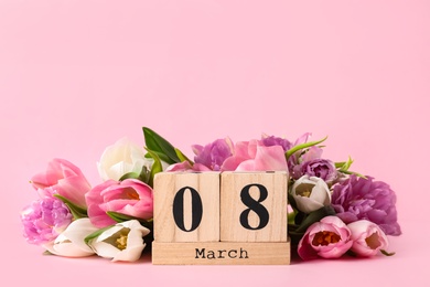 Photo of Wooden block calendar with date 8th of March and tulips on pink background, space for text. International Women's Day