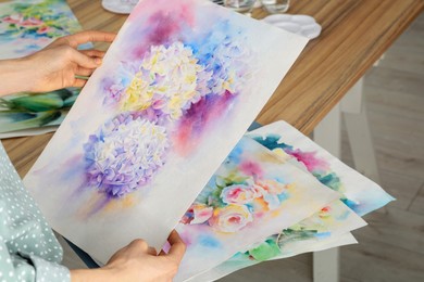 Woman holding painting of flowers indoors, closeup. Watercolor artwork