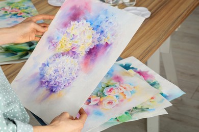 Photo of Woman holding painting of flowers indoors, closeup. Watercolor artwork