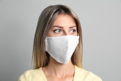 Photo of Young woman in protective face mask on light grey background