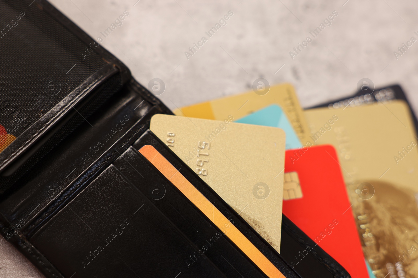 Photo of Many different credit cards and leather wallet on grey table, closeup