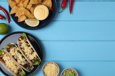 Flat lay composition with delicious tacos on light blue wooden table, space for text