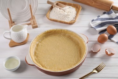 Photo of Pie tin with fresh dough and ingredients on white wooden table. Making quiche