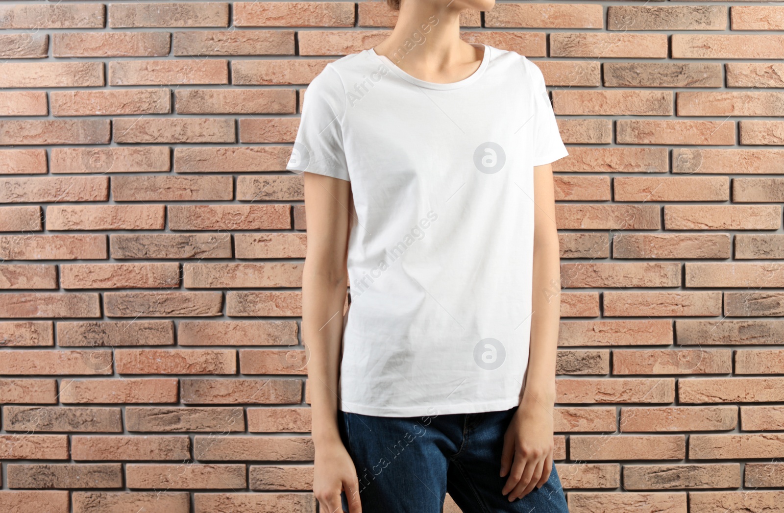 Photo of Woman in white t-shirt near brick wall. Mock up for design