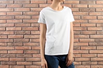 Photo of Woman in white t-shirt near brick wall. Mock up for design