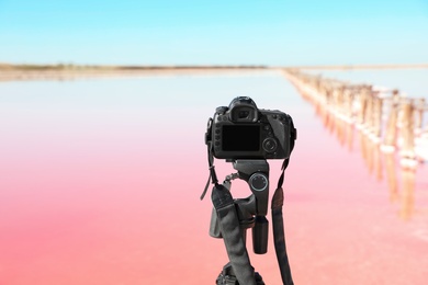 Photo of Professional camera with tripod near pink lake