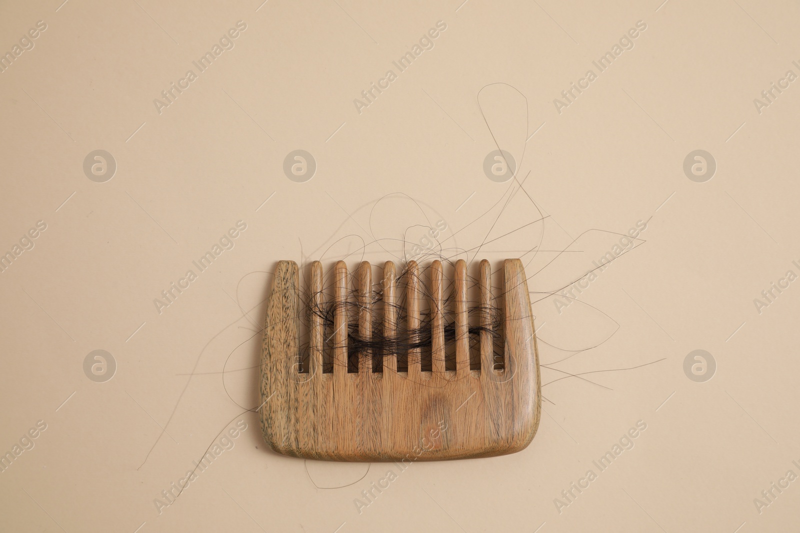 Photo of Wooden comb with lost hair on beige background, top view. Space for text