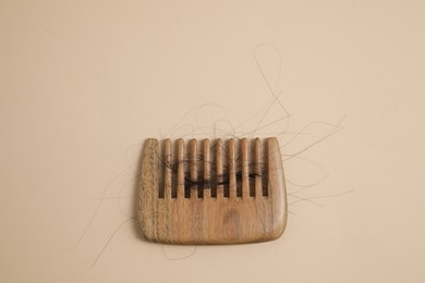 Photo of Wooden comb with lost hair on beige background, top view. Space for text