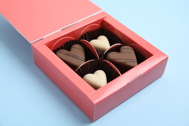 Tasty heart shaped chocolate candies on light blue background. Happy Valentine's day