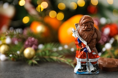 Photo of Chocolate Santa Claus candy on grey table, space for text