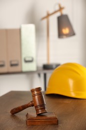 Photo of Law concept. Gavel and yellow hard hat on wooden table