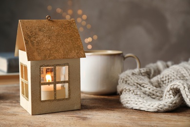 Composition with house shaped candle holder on wooden table. Christmas decoration