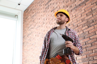 Photo of Young working man with screwdriver near brick wall. Space for text