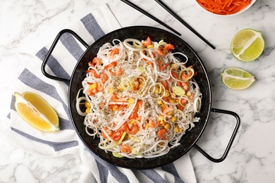Photo of Flat lay composition with rice noodles in frying pan on marble background
