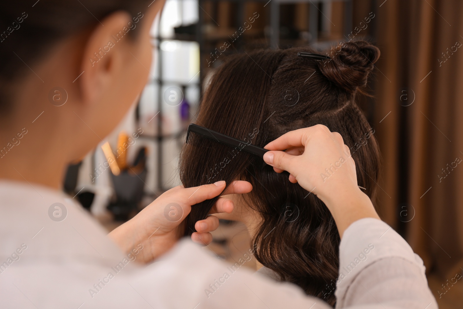 Photo of Stylist working with client in salon, making hairstyle