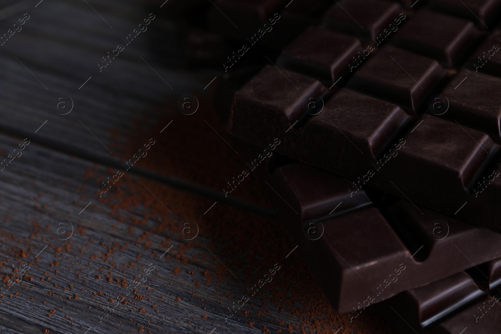 Photo of Tasty dark chocolate bars on wooden table. Space for text