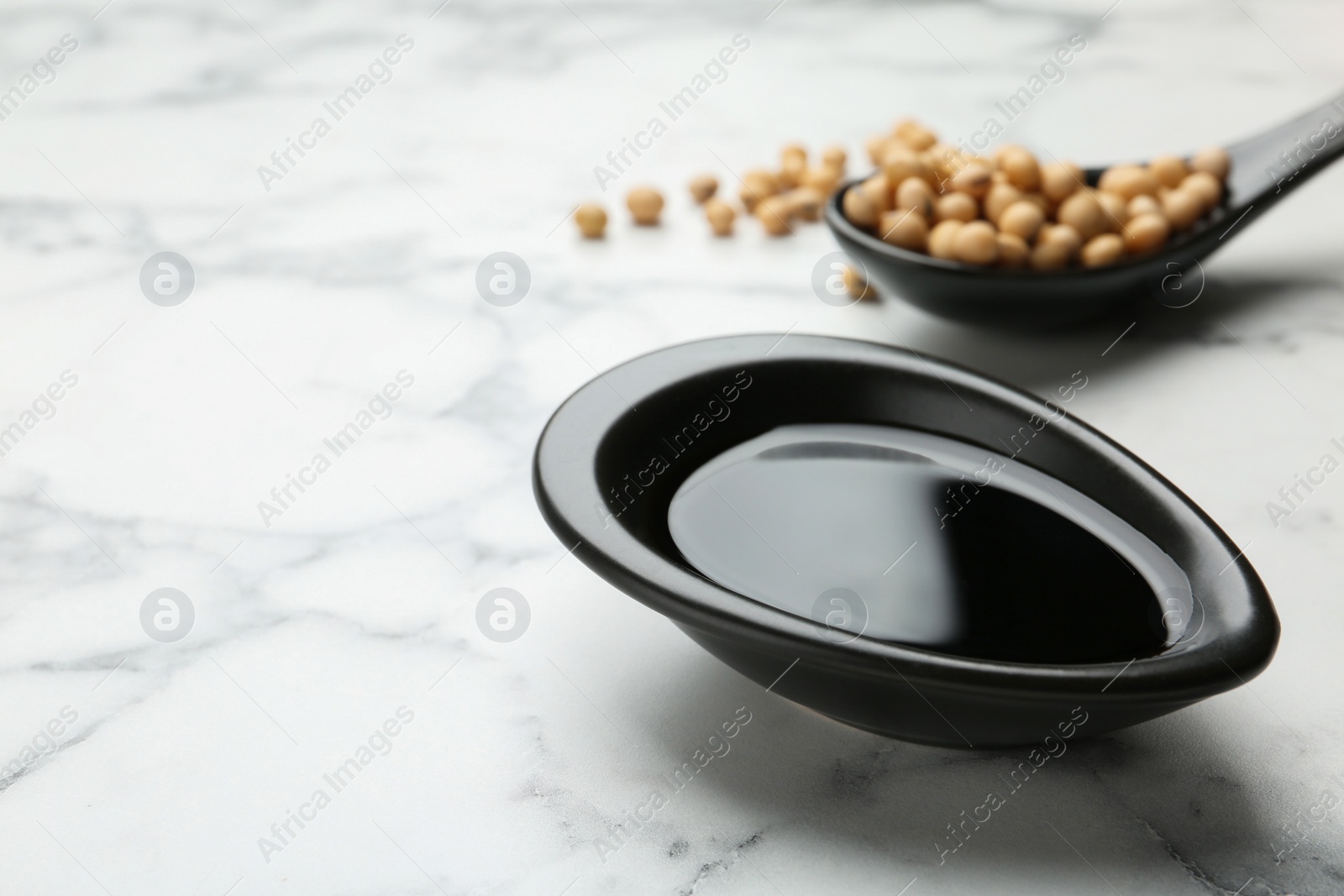 Photo of Dish of soy sauce and beans on table. Space for text