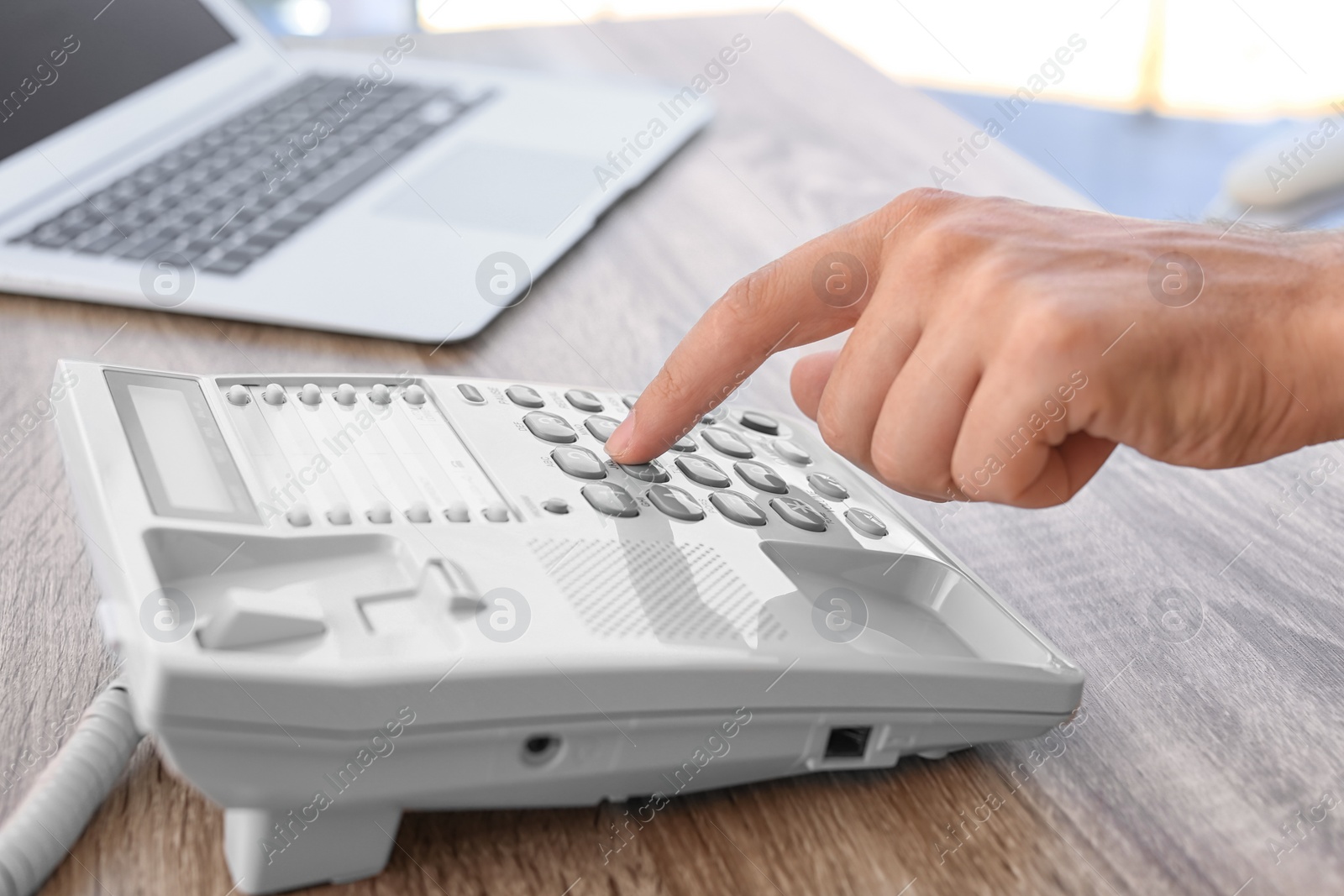 Photo of Man dialing number on telephone at workplace