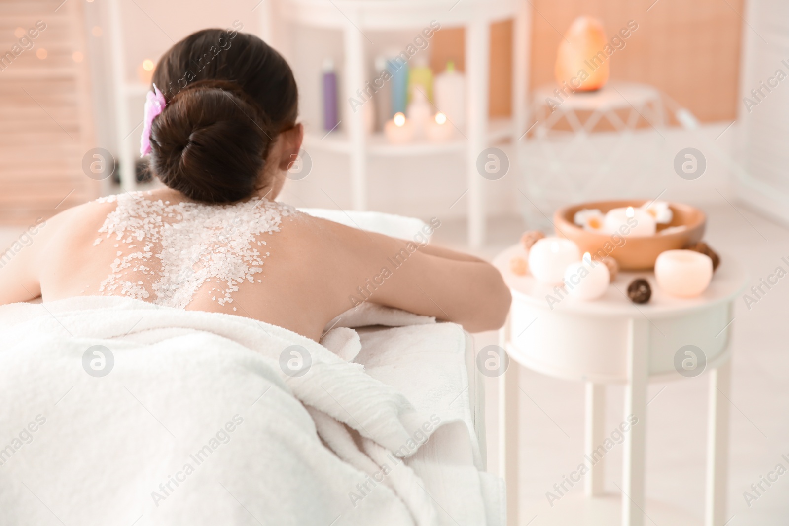 Photo of Beautiful young woman with body scrub on her back in spa salon