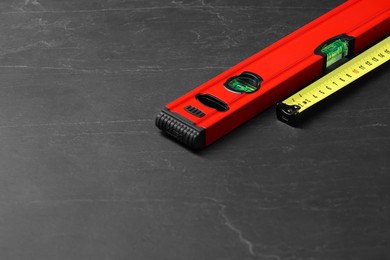 Photo of Building level and tape measure on black table. Space for text