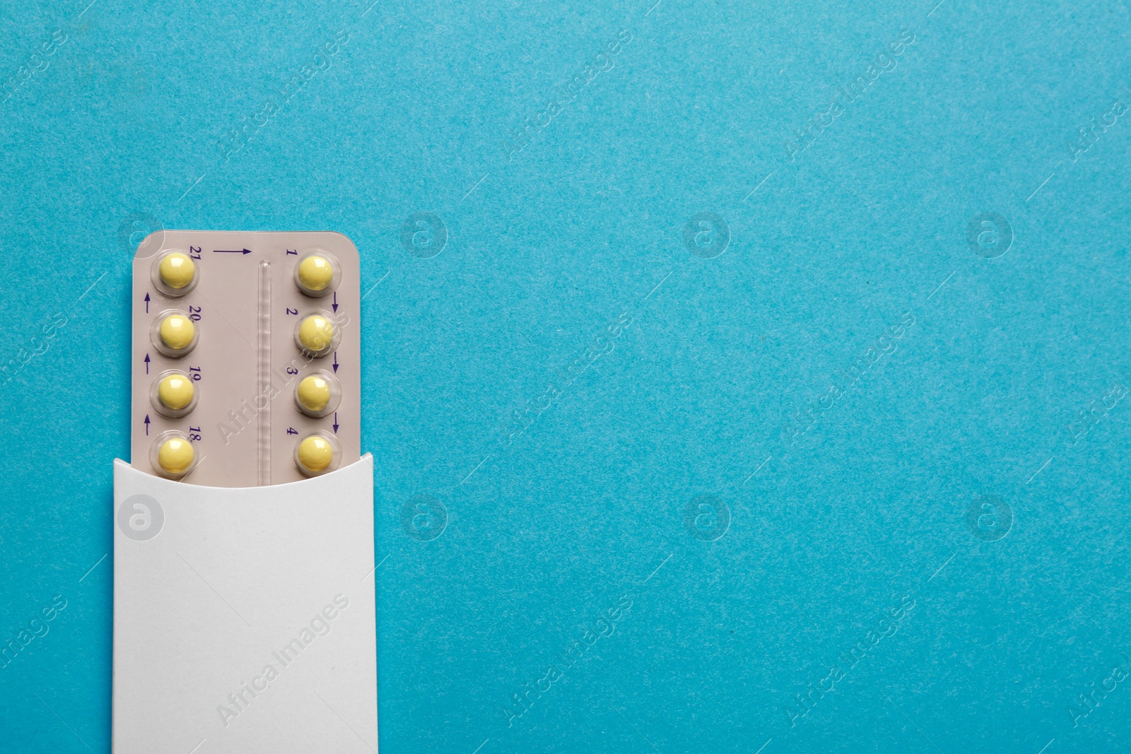Photo of Birth control pills on light blue background, top view. Space for text