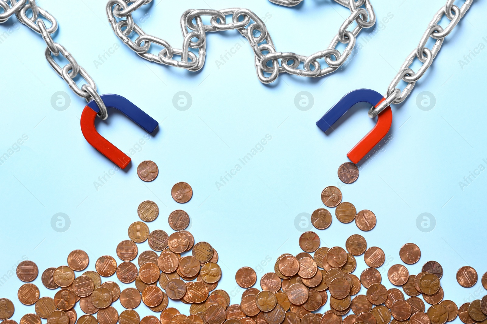 Photo of Chain with magnets attracting coins on light blue background, flat lay