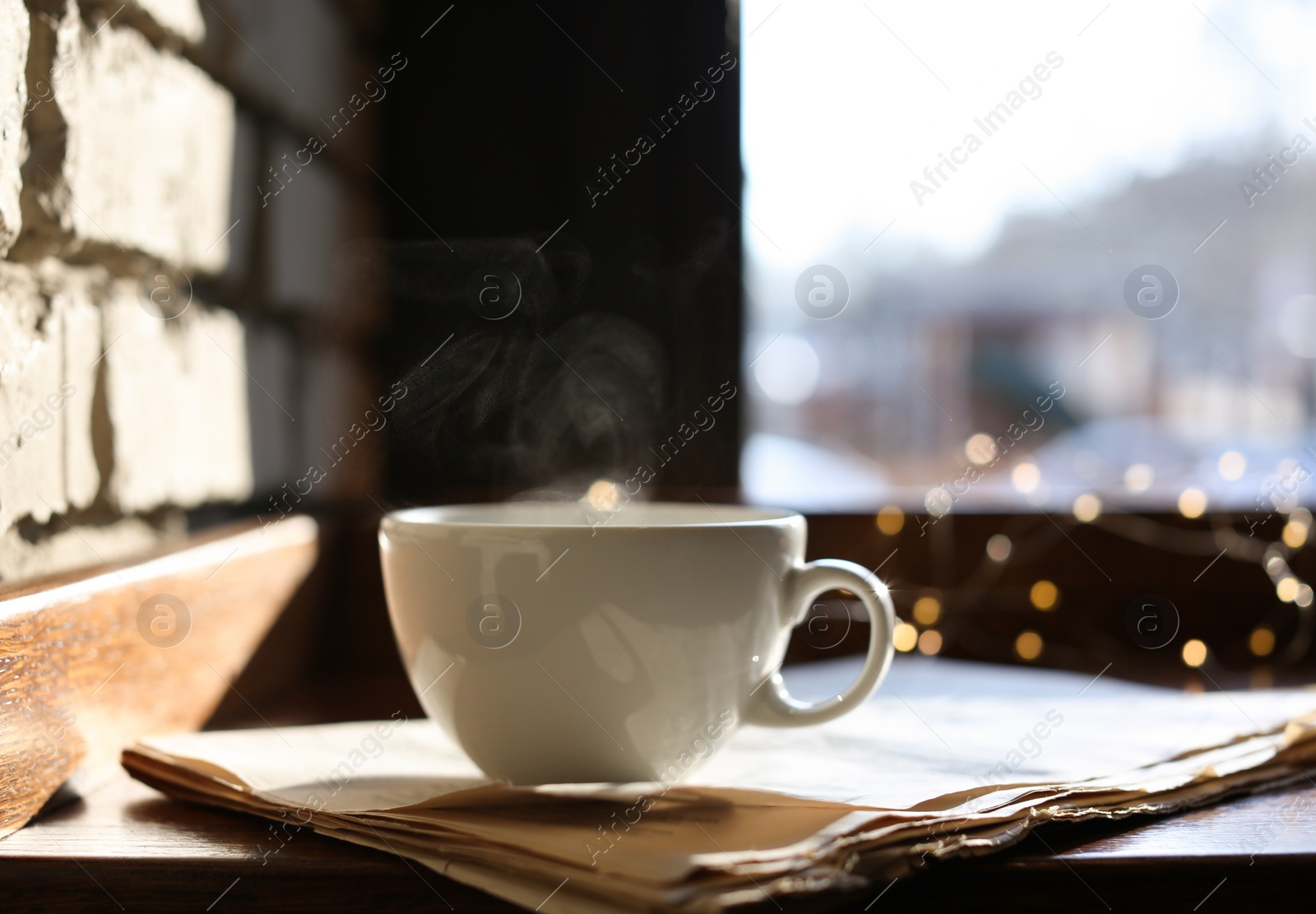 Photo of Delicious morning coffee and newspaper near brick wall, indoors