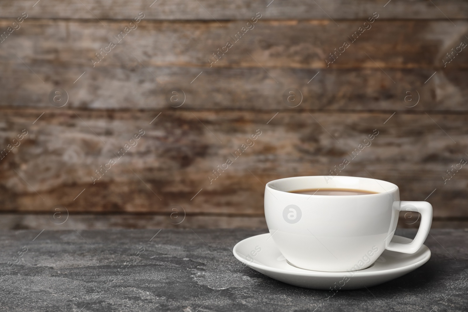 Photo of White ceramic cup with hot aromatic coffee on table