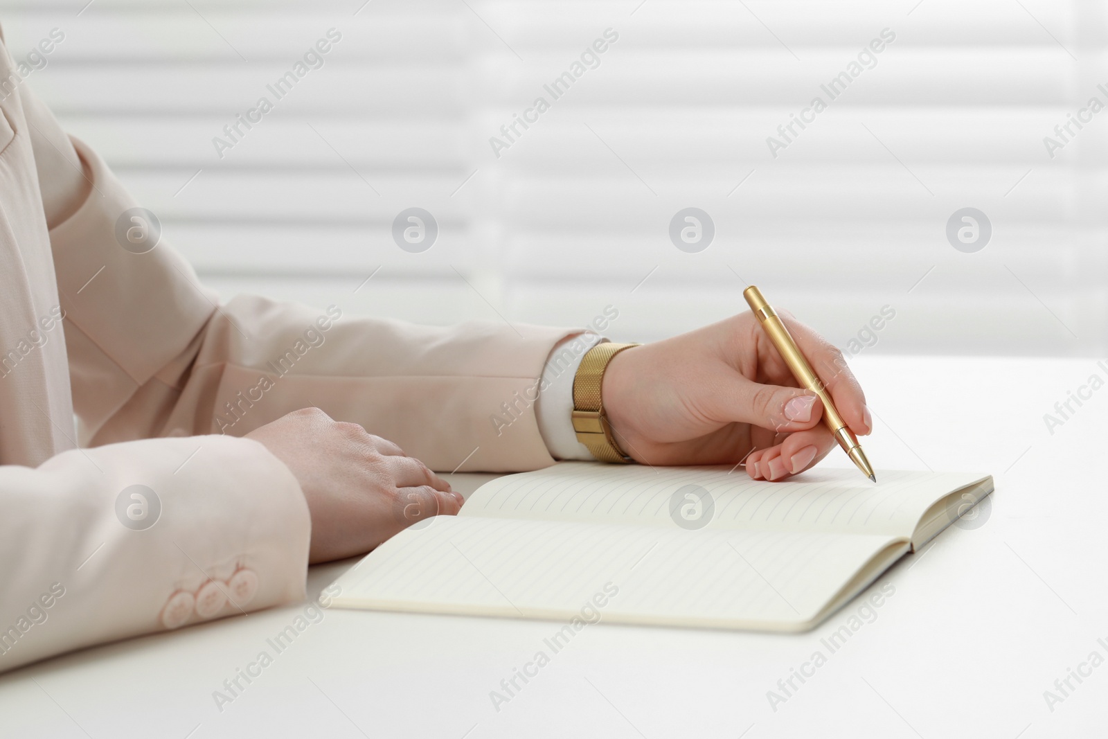 Photo of Woman writing in notebook at white table, closeup