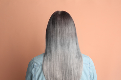 Image of Woman with gray hair on pale pink background, back view