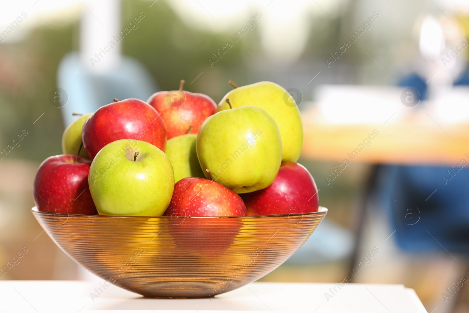 Photo of Bowl with different sweet apples on table in room, closeup