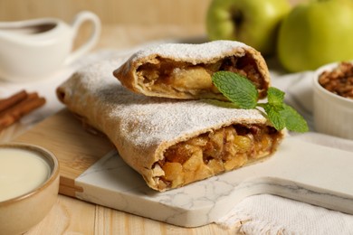 Delicious strudel with apples, nuts and raisins on wooden table, closeup