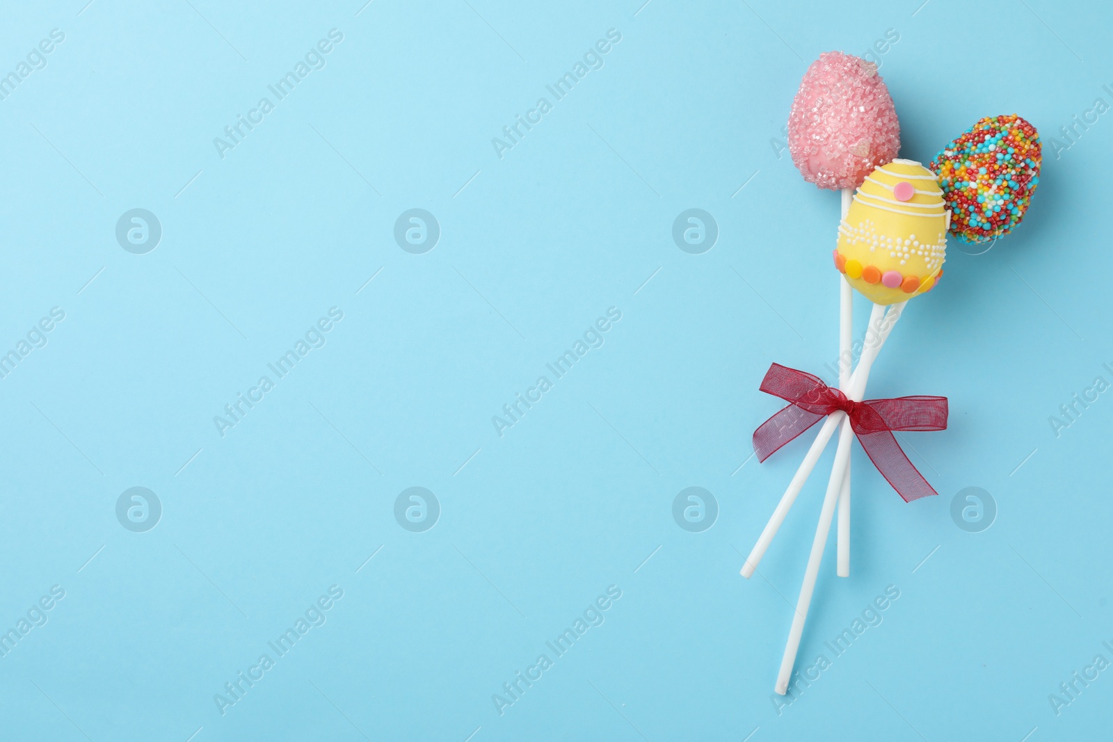 Photo of Egg shaped cake pops and space for text on light blue background, top view. Easter celebration