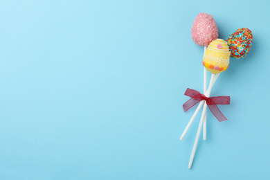 Photo of Egg shaped cake pops and space for text on light blue background, top view. Easter celebration